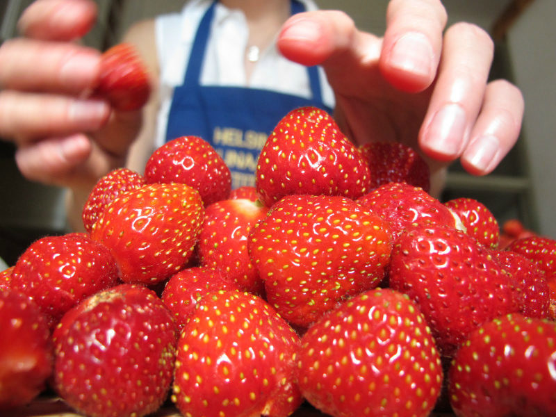 The girl's hand reaches for the grief of fresh strawberries