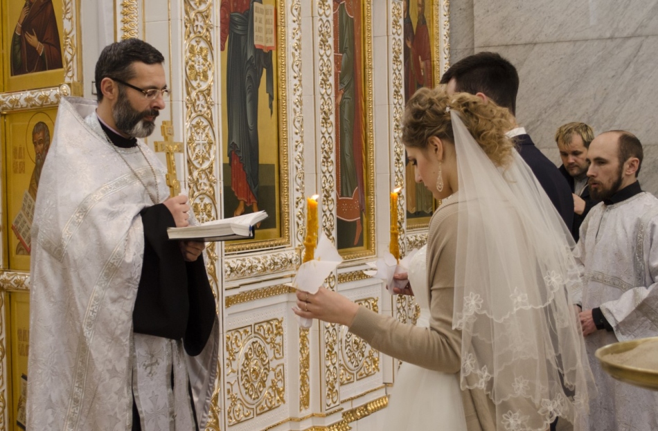 Mladi držijo sveče med poroko