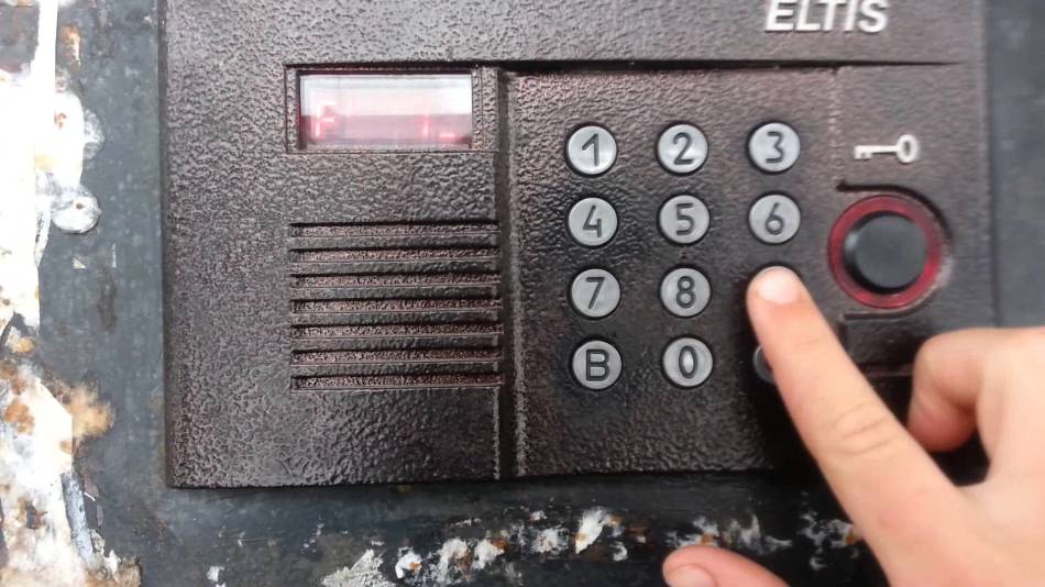 Egy személy tárcsáz egy kódot az ajtó kinyitásához egy intercom -os Eltis -rel