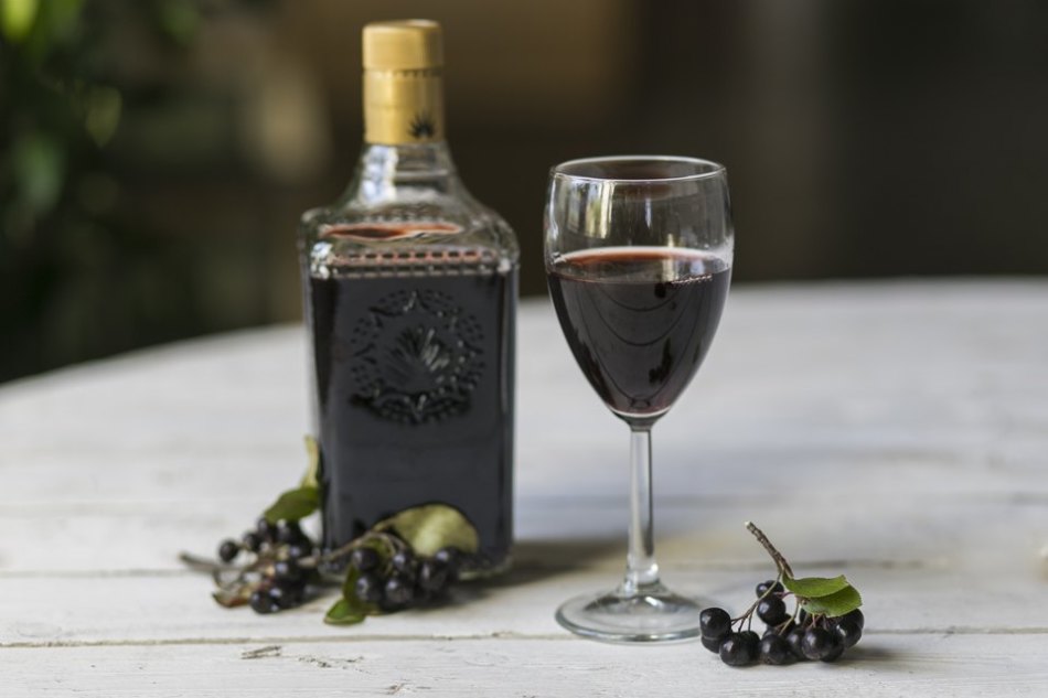 Steklenica, kozarec domačega vina in grozdov iz črnega ribeza